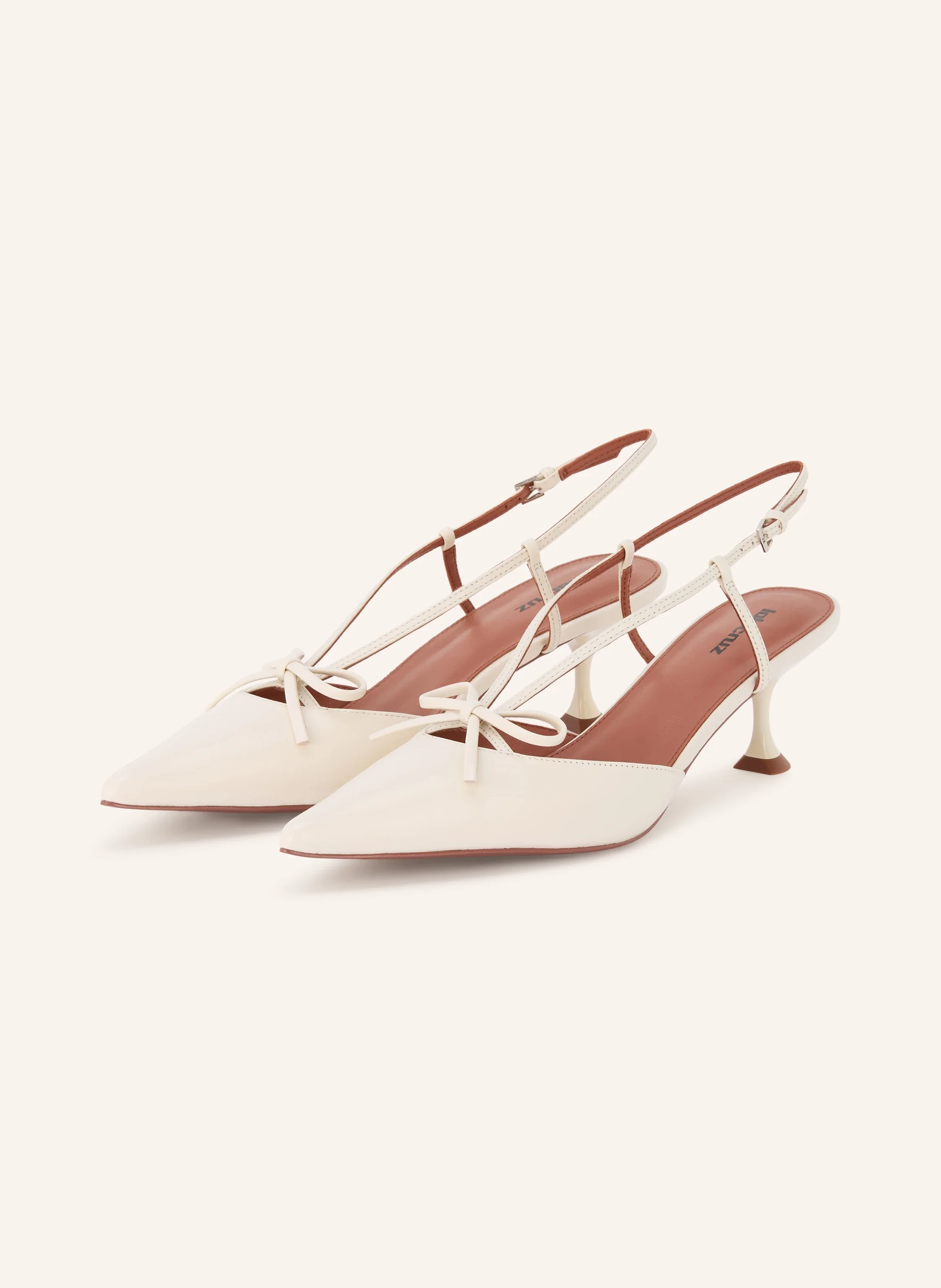Cremeweiße Slingback-Pumps von Lola Cruz mit spitzer Zehenkappe, filigranen Riemchen mit kleiner Schleife und niedrigem Kitten-Heel-Absatz vor hellem Hintergrund.