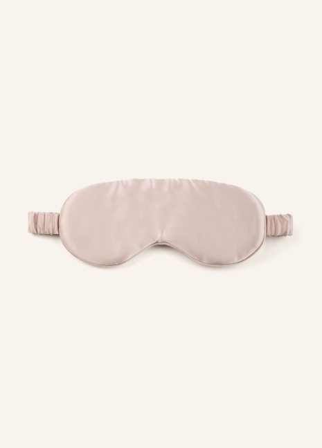Eine elegante Schlafmaske aus glänzender, zartrosafarbener Seide mit einem gerafften, elastischen Halteband auf hellem Hintergrund.