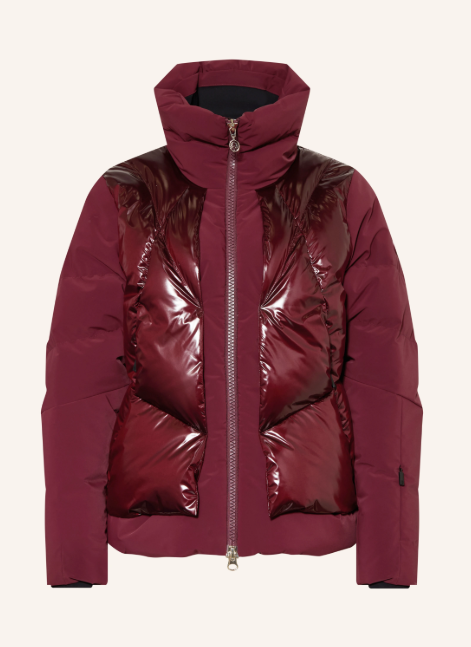 Eine bordeauxrote Skijacke mit hohem Stehkragen und durchgehendem Frontreißverschluss. Das Design zeichnet sich durch einen auffälligen Materialmix aus matten Ärmeln und einer hochglänzenden, gesteppten Frontpartie aus.