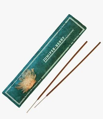 Juniper Berry Räucherstäbchen in dunkelgrüner Verpackung mit floraler Illustration – zwei naturbelassene Stäbchen liegen daneben.