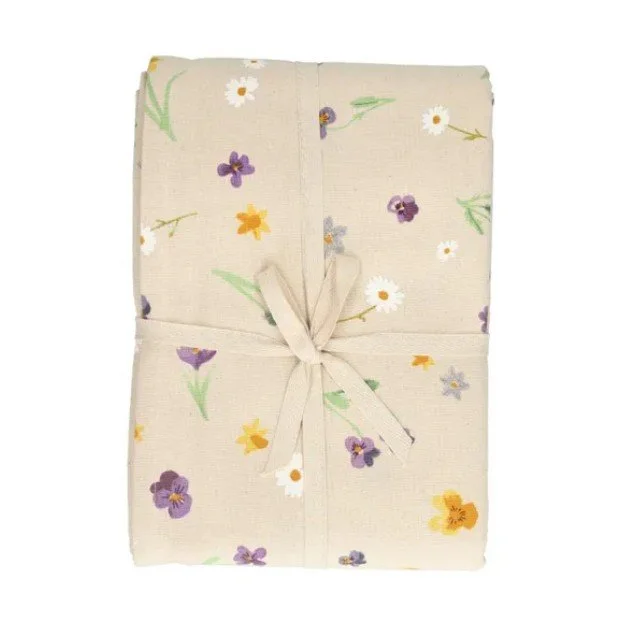 Zusammengefaltete beige Tischdecke von Dille & Kamille mit einem Muster aus kleinen Wildblumen (Veilchen und Gänseblümchen), gebunden mit einem Stoffband.