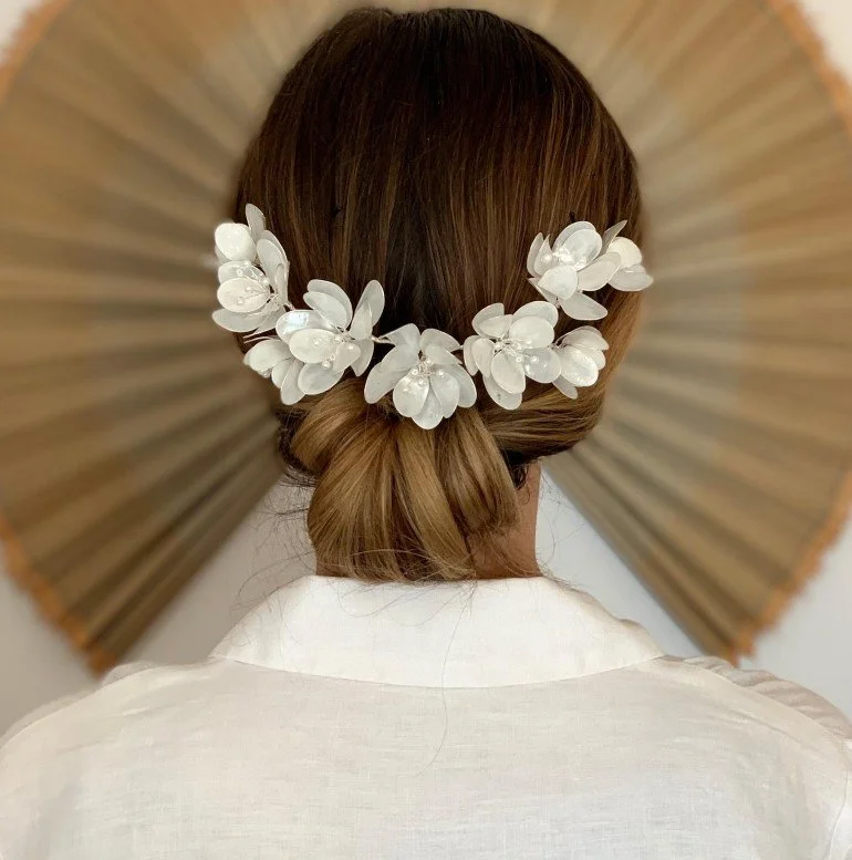 Rückenansicht einer Braut mit tiefem Dutt und einem floralen Diadem für die Hochzeit aus weißen Blüten.