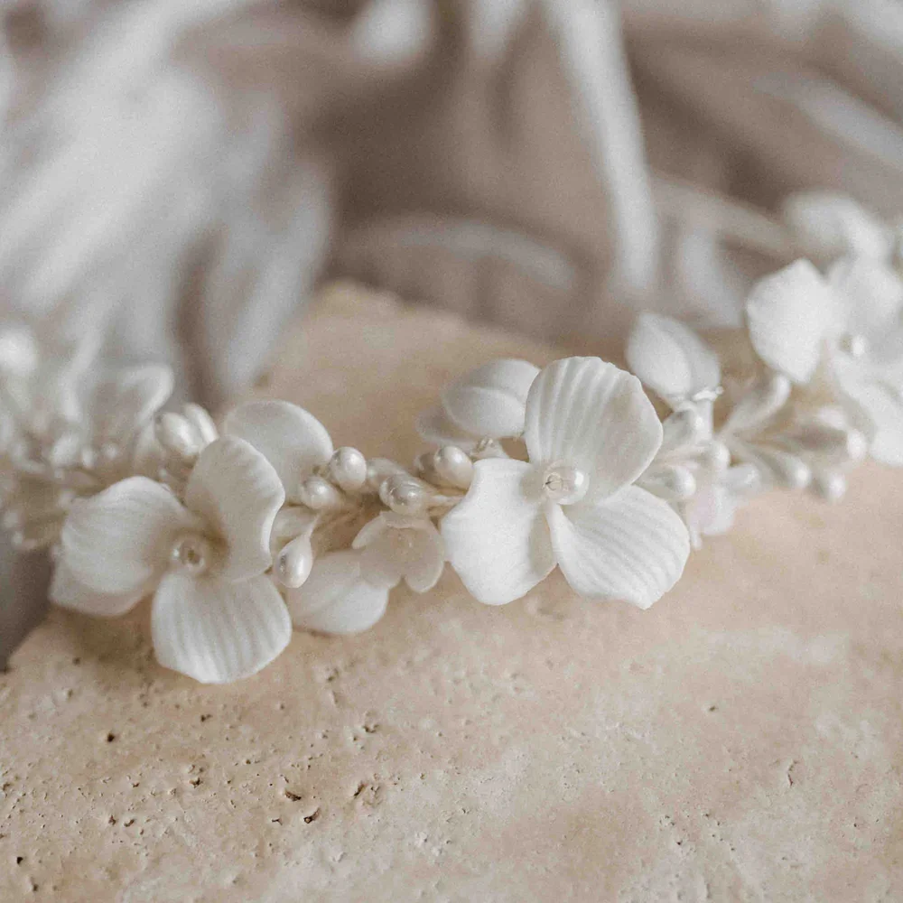 Detailaufnahme eines weißen, floralen Diadems für die Hochzeit mit zarten 3D-Blüten und feinen Perlen.