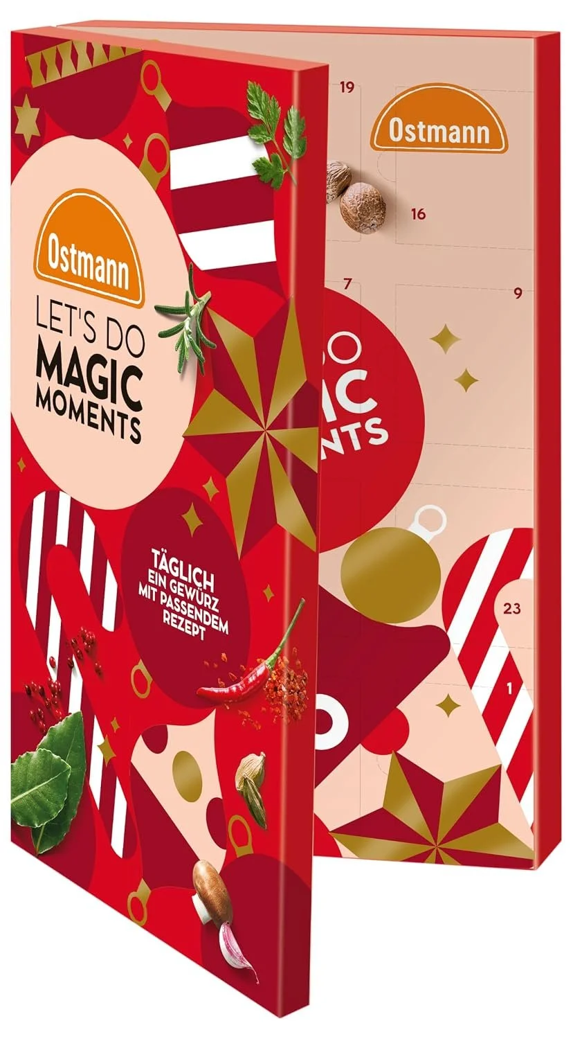 Roter, aufklappbarer Ostmann-Gewürzkalender im Buchformat. Die Vorderseite zeigt verschiedene Gewürze, den Titel „LET’S DO MAGIC MOMENTS“ und verspricht tägliche Rezepte. Im leicht geöffneten Inneren sind nummerierte Türchen sichtbar.