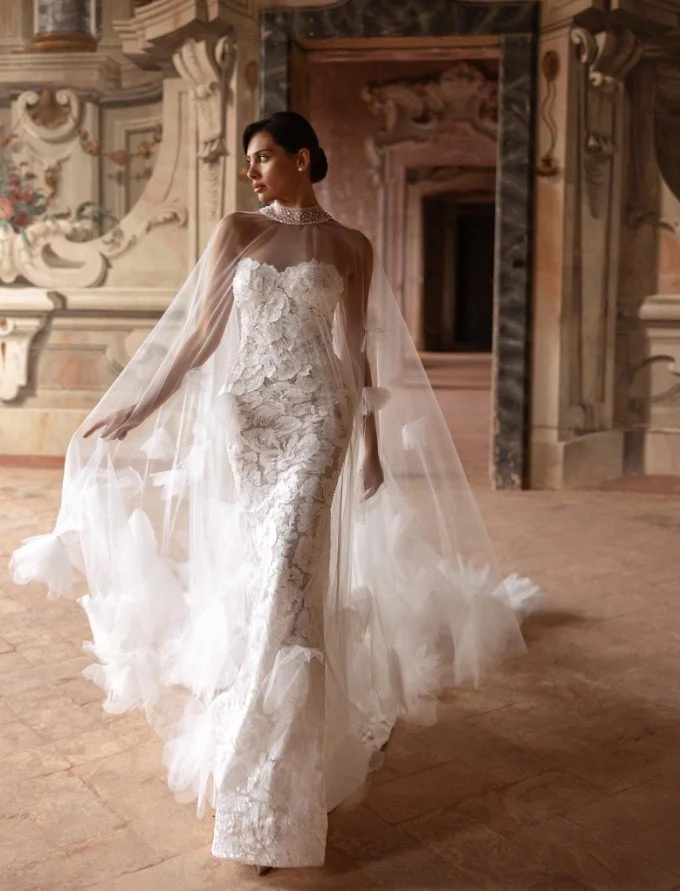 Figurbetontes Spitzen-Brautkleid mit glamourösem, transparentem Tüll-Cape und Stehkragen.