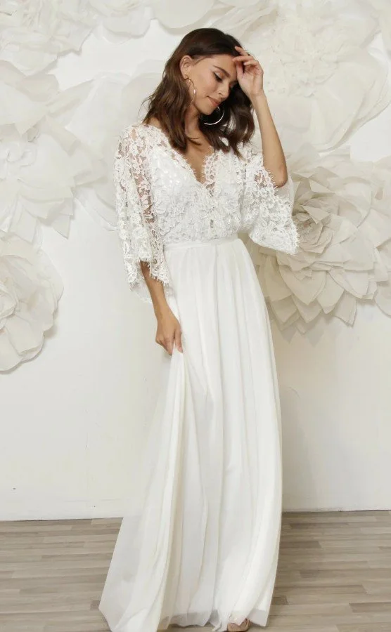 Fließendes Boho-Hochzeitskleid mit weiten Spitzenärmeln und leichtem Rock in Ganzkörperansicht.
