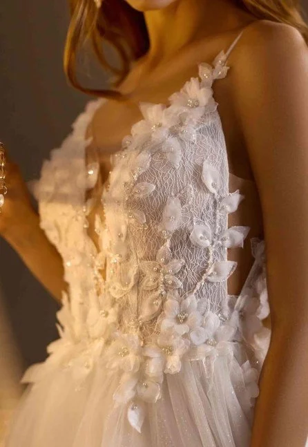 Romantisches Brautkleid-Detail mit zarten floralen Applikationen und feiner Spitze, das durch dezente Perlen einen sanften Schimmer erhält.