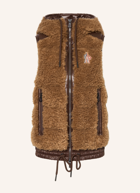 Eine ärmellose, braune Weste in flauschiger Teddy-Optik mit Frontreißverschluss, Reißverschlusstaschen, dunklen Kontrastdetails und einem Kordelzug am Saum.