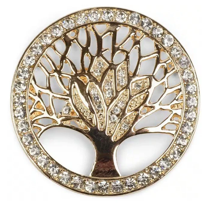 Eine runde, goldfarbene Brosche mit dem Motiv des Lebensbaums. Der äußere Rand ist komplett mit kleinen, klaren Kristallen besetzt, und auch die Äste des Baumes funkeln durch feine Schmucksteine. Hochwertiger Broschen Schmuck vor weißem Hintergrund.