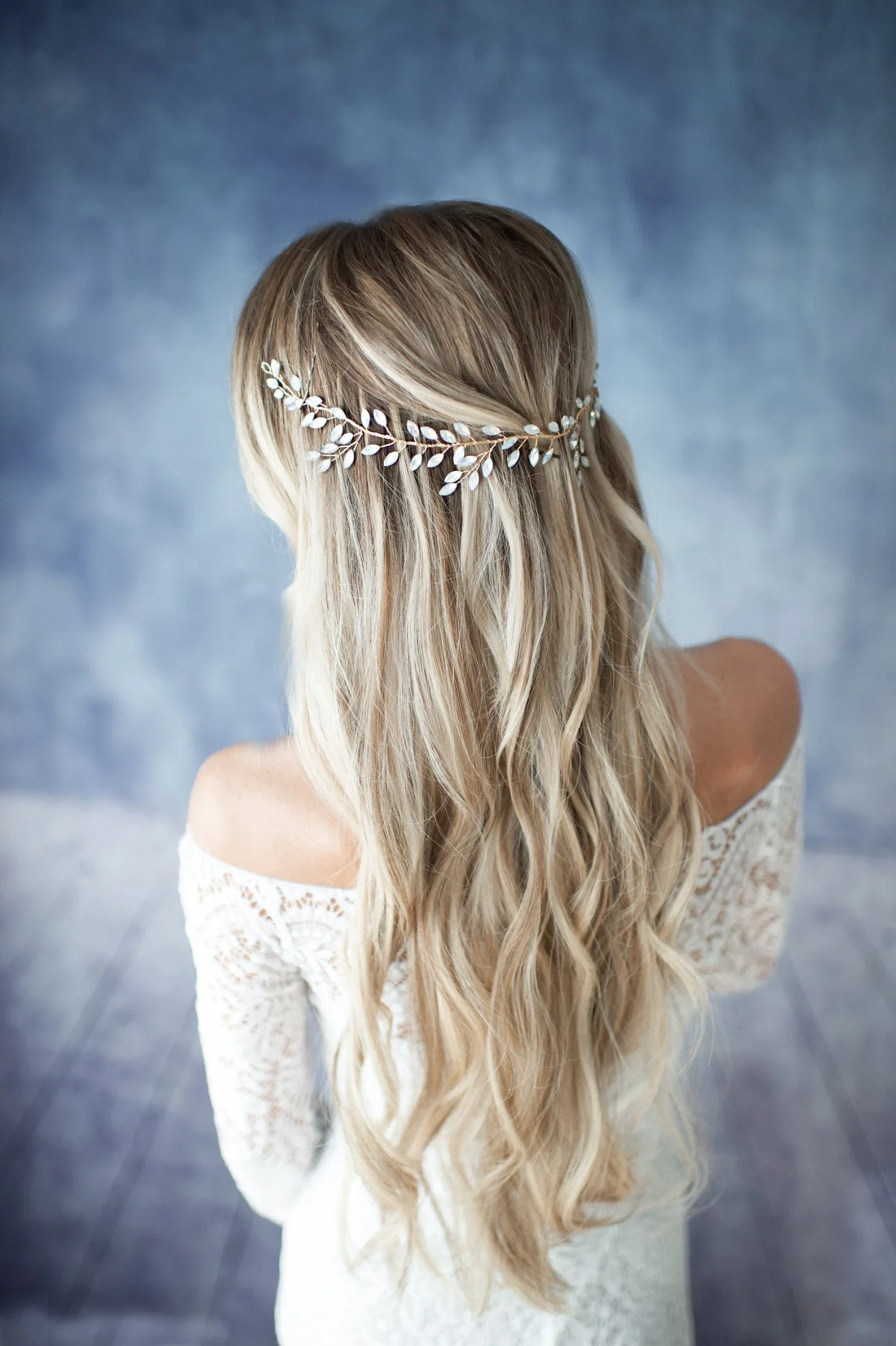 Boho-Braut mit offenen, welligen Haaren und einem filigranen, goldenen Blätter-Diadem für die Hochzeit.