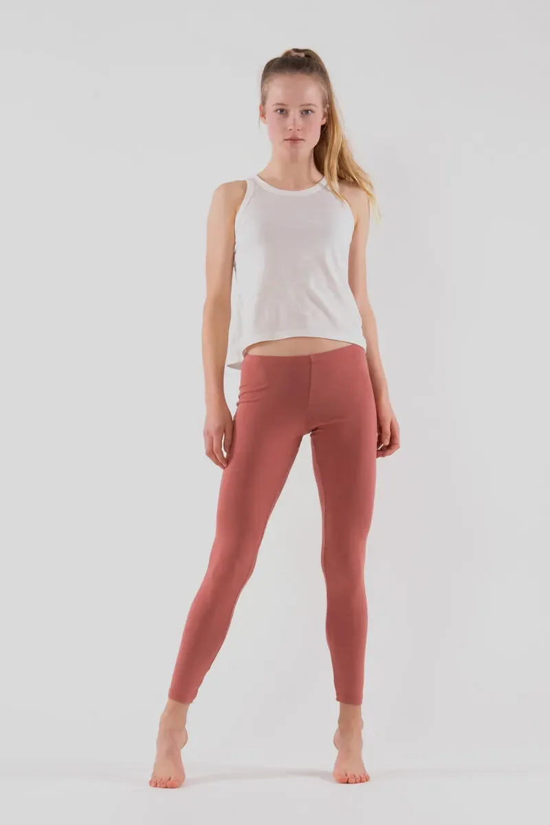 Frau in weißem Top und altrosafarbenen Leggings vor hellem Hintergrund