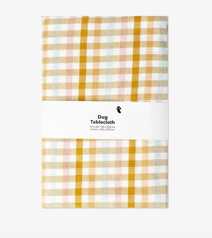 Verpackte Tischdecke von Flying Tiger mit einem großen Karomuster (Gingham) in Gelb, Weiß und zarten Pastelltönen.