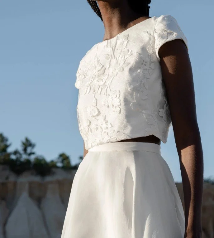Zweiteiliges Brautkleid mit floralem Spitzen-Crop-Top und schlichtem Rock.