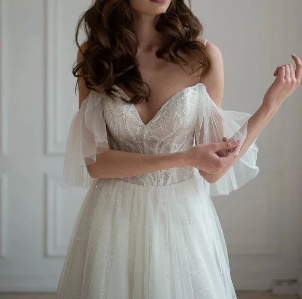Glitzerndes Brautkleid mit Spaghettiträgern und luftigen Off-Shoulder-Tüllärmeln.