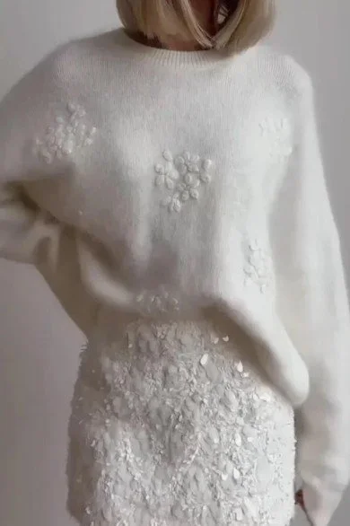 Weiße Brautmode mit besticktem Pullover und kurzem Rock in floraler Struktur – eleganter und moderner Hochzeitslook für 2026.