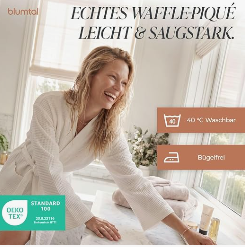 Lachende Frau in weißem blumtal Bademantel. Bildtext bewirbt das Material als echtes Waffel-Piqué, leicht, saugstark, 40°C waschbar, bügelfrei und Oeko-Tex zertifiziert.