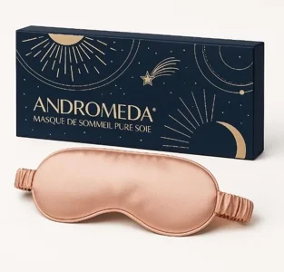 Luxuriöse Schlafmaske aus reiner Seide in Rosé von Andromeda, präsentiert vor dunkelblauer Verpackung mit goldenen Sternen und Himmelsmotiven.