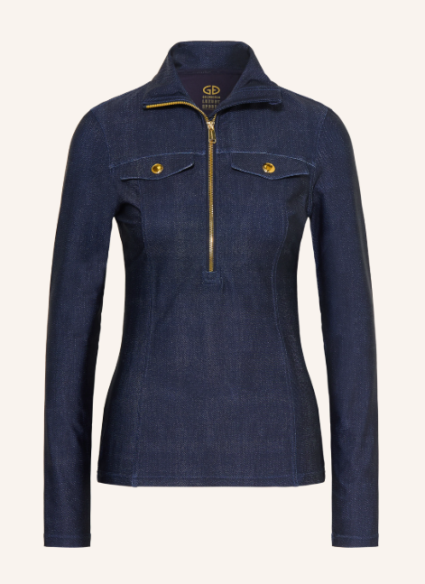 Ein figurbetontes, dunkelblaues Langarm-Oberteil in Denim-Optik mit einem goldenen halben Reißverschluss und zwei kleinen Brusttaschen.