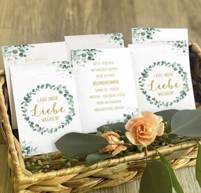 Gastgeschenk zur Hochzeit in Form von liebevoll gestalteten Tütchen mit Blumensamen und dem Aufdruck „Lasst unsere Liebe wachsen“, dekorativ in einem Korb mit Blumen arrangiert.