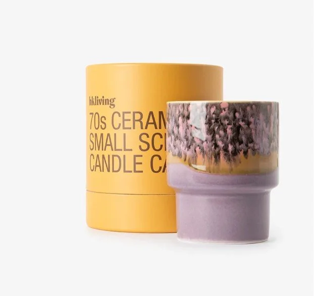 Keramik-Duftkerze im 70er-Jahre-Stil in Gelb- und Lilatönen mit Verpackung, dekorative Geschenkidee für Frauen, freigestellt auf weißem Hintergrund.