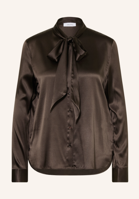 Dunkelbraune Schluppenbluse aus schimmerndem Satin mit elegant gebundener Schleife am Kragen vor hellem Hintergrund. Langärmelige Damenbluse mit durchgehender Knopfleiste und Manschetten.