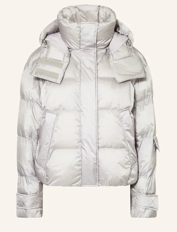 Voluminöse Steppjacke (Puffer Jacket) in der Trendfarbe 2026 Cloud Dancer. Die Winterjacke in schimmerndem, hellem Silbergrau verfügt über einen hohen Stehkragen und eine Kapuze – ein modernes Statement-Piece für kalte Tage.