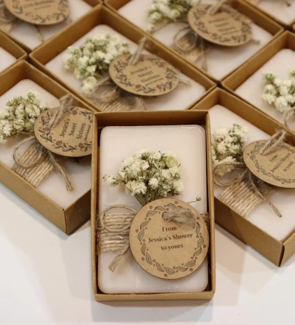 Rustikal verpackte Gastseifen: weiße Seifen in braunen Kartonboxen, dekoriert mit Naturband, getrocknetem Schleierkraut und runden Kraftpapier-Anhängern — ideal für Hochzeiten oder Bridal Showers.