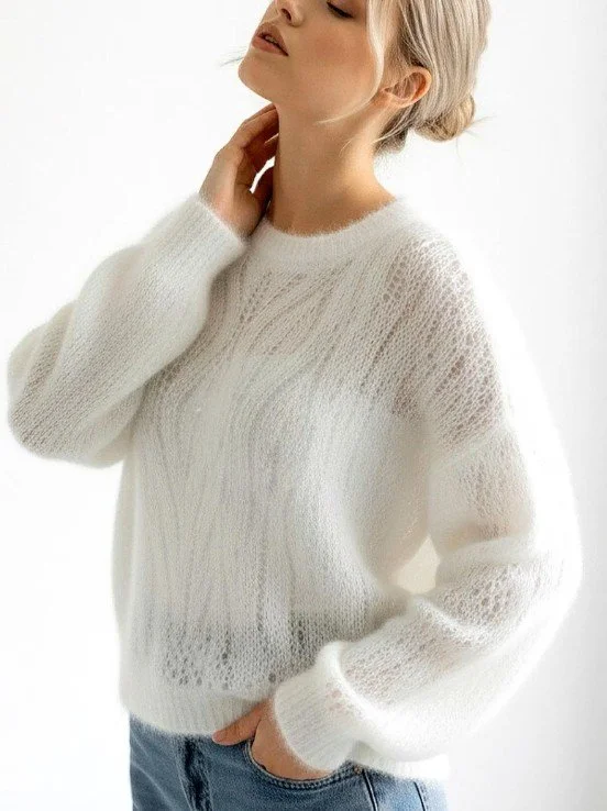 Frau mit blonden Haaren trägt weichen, weißen Brautpullover aus Mohair mit leichtem Muster und kombiniert ihn lässig mit einer Jeans.