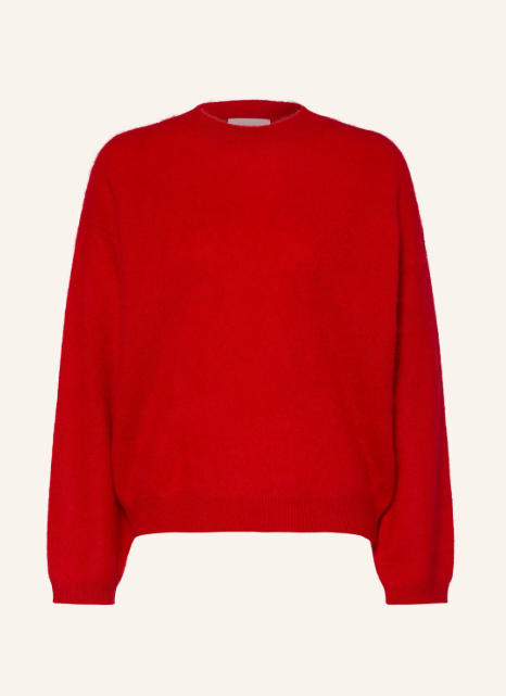 Roter Langarm Pullover aus flauschigem Feinstrick mit Rundhalsausschnitt und leicht überschnittenen Schultern vor hellem Hintergrund. Weicher Strickpullover mit feinen Rippbündchen an Hals, Ärmelenden und Saum.