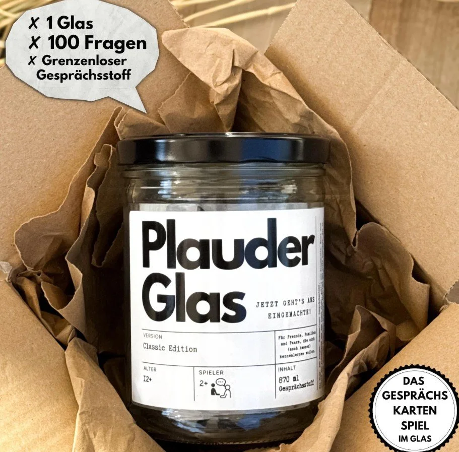 Ein Glas mit dem Etikett „Plauderglas“ liegt in einem Karton – es enthält 100 Gesprächskarten für Paare oder Freunde, ideal als Geschenk zum Valentinstag.