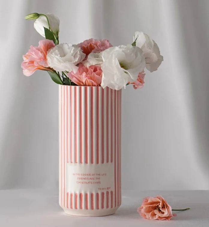 Rosa-weiß gestreifte Keramikvase mit einem Blumenstrauß aus rosa und weißen Eustoma-Blüten und einem englischen Freundschafts-Spruch über BFFs und Chocolate Chips.