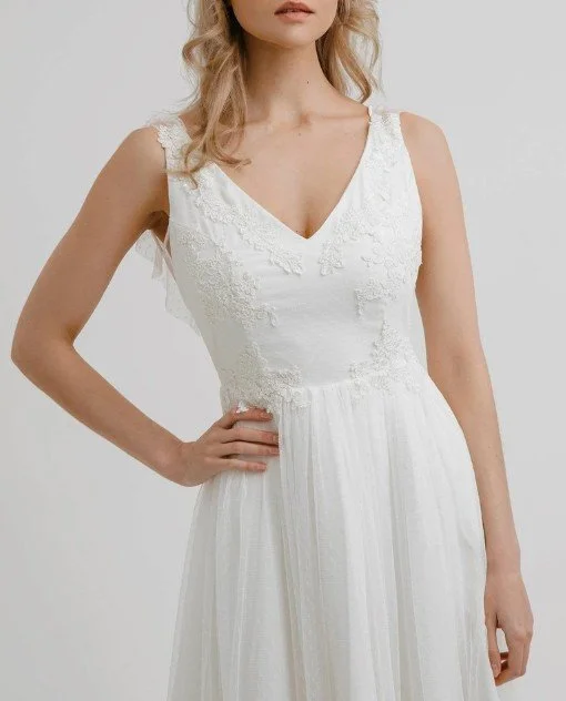 Oberteil eines romantischen Brautkleides mit V-Ausschnitt, verziert mit feinen floralen Spitzenapplikationen, die sanft in den Tüllrock übergehen.