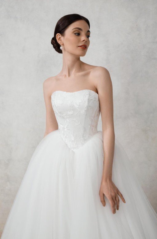 Trägerloses Korsett-Brautkleid mit herzförmigem Ausschnitt, verziert mit feiner floraler Spitzenstickerei, kombiniert mit einem voluminösen Rock aus weißem Tüll.