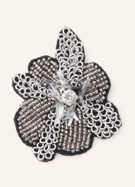 Eine blumenförmige Brosche aus dunkelgrauen Perlen und silberfarbener Stickerei, verziert mit einem klaren Schmuckstein und Pailletten in der Mitte.