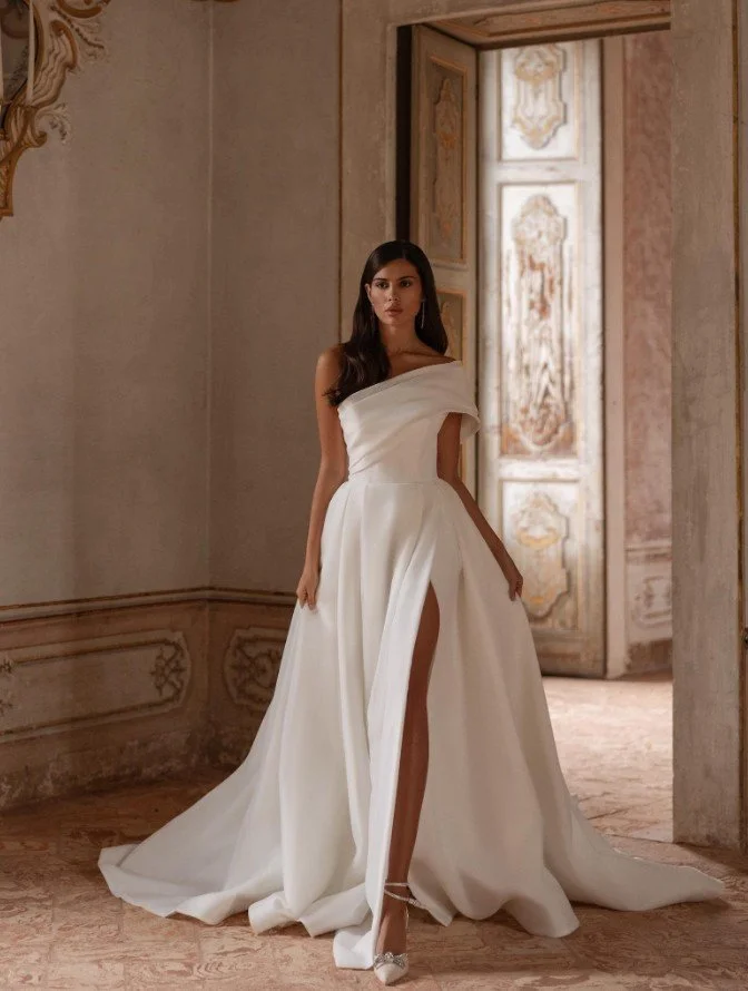 Modernes One-Shoulder Satin-Brautkleid mit hohem Beinschlitz und Drapierung.