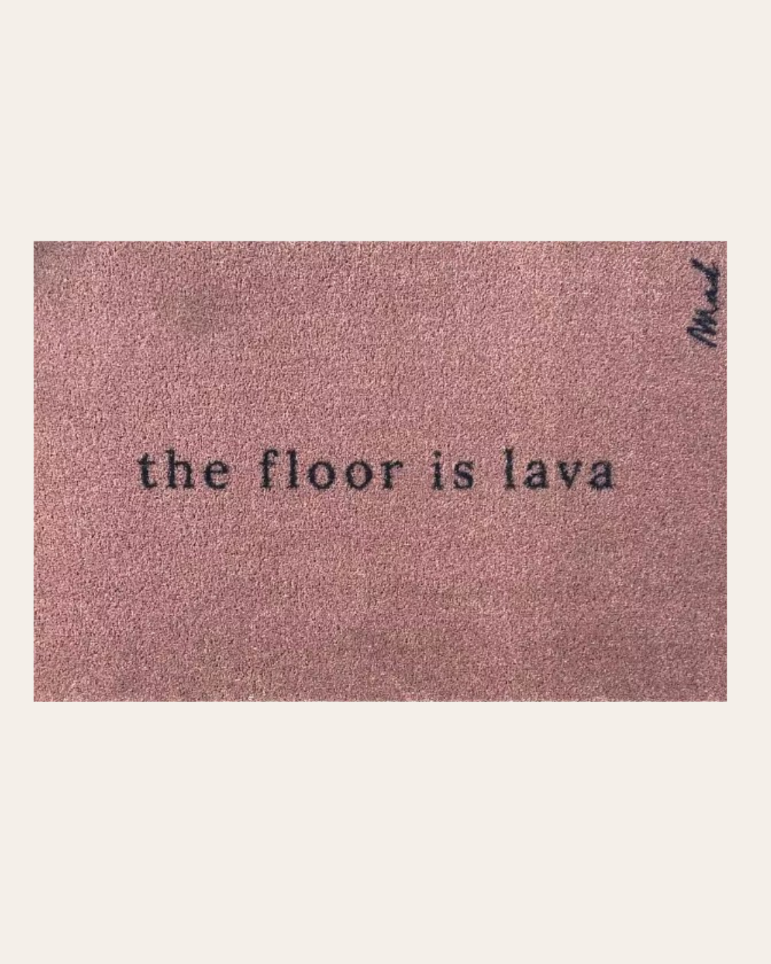 Rechteckige Fußmatte in Altrosa mit dem humorvollen, schwarzen Schriftzug „the floor is lava“ in Schreibmaschinen-Optik.
