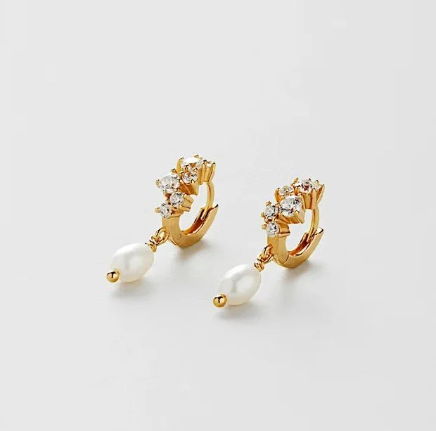 Kleine goldene Creolen (Huggies) mit besetzten Zirkonia-Kristallen und hängender weißer Perle. Moderner, funkelnder Brautschmuck von Safira, perfekt als trendige Brautohrringe.