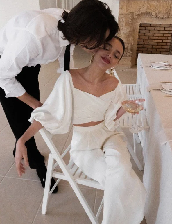 Romantisches A-Linien-Brautkleid mit Spaghettiträgern, 3D-Blüten-Korsage und Tüllrock im Gegenlicht.