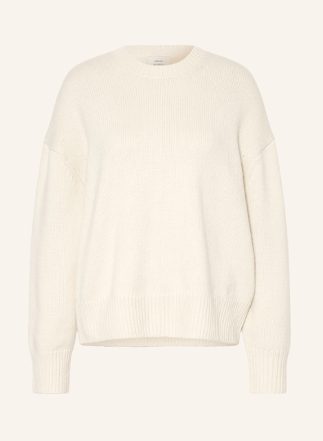 Crèmeweißer Langarm Pullover aus dichtem Feinstrick mit Rundhalsausschnitt und überschnittenen Schultern. Lockerer Strickpullover vor hellem Hintergrund. Rippbündchen an Hals, Ärmelenden und breitem Saum.