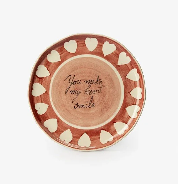Keramikteller in Rosé- und Beigetönen mit Herzrand und Schriftzug „You make my heart smile“, romantische Geschenkidee für Frauen zum Valentinstag, freigestellt auf weißem Hintergrund.