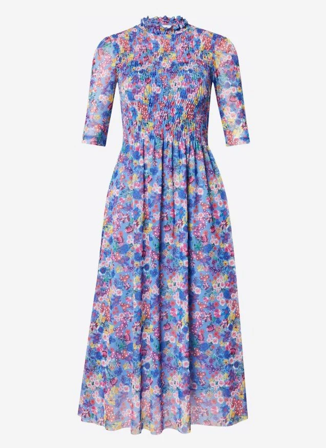Langes, florales Hochzeitsgast-Kleid in kräftigem Blau-Lila mit buntem Blumenmuster, halblangen Ärmeln und schmaler, gesmokter Taille. Das Kleid wirkt luftig, elegant und ist perfekt für eine sommerliche Hochzeit geeignet.