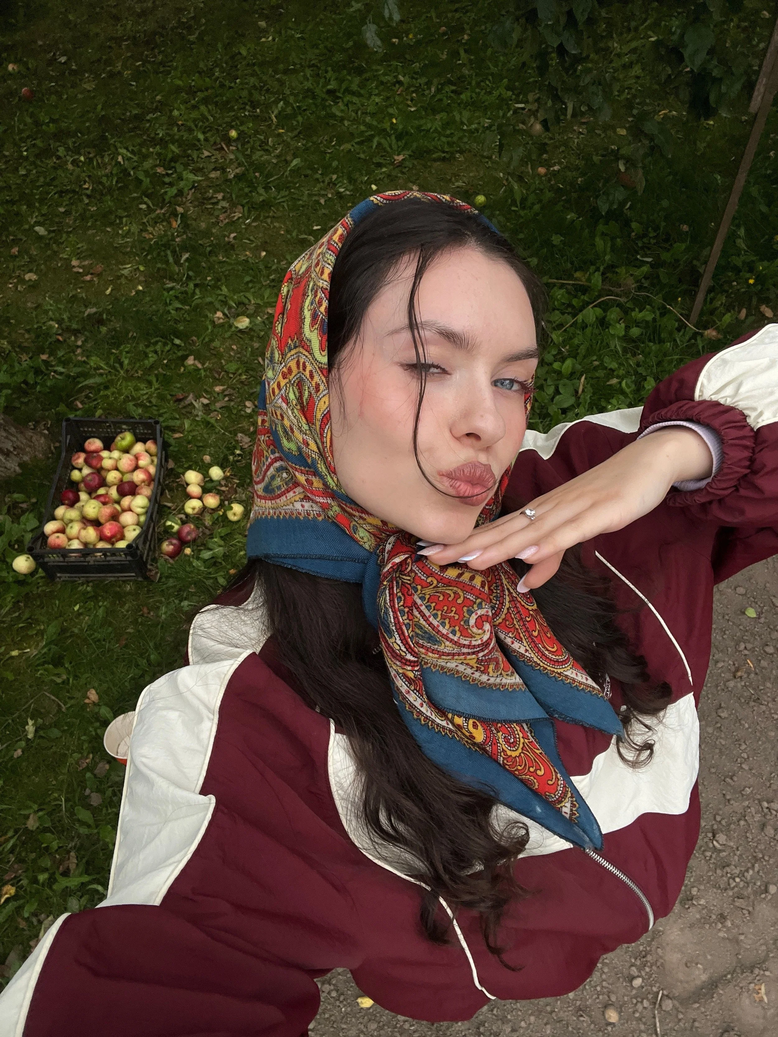 Frau mit rot-blauem Kopftuch im Paisleymuster und bordeauxfarbener Vintage-Jacke im herbstlichen Garten