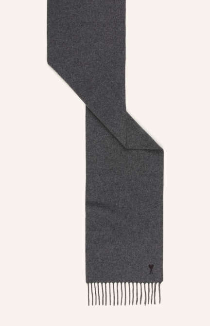 Ein dunkelgrauer Wollschal, der in der Mitte gefaltet ist. Er hat klassische Fransen an den Enden und zeigt ein kleines, schwarzes Ami Paris Logo (ein Herz mit einem "A" darunter) am unteren rechten Rand.