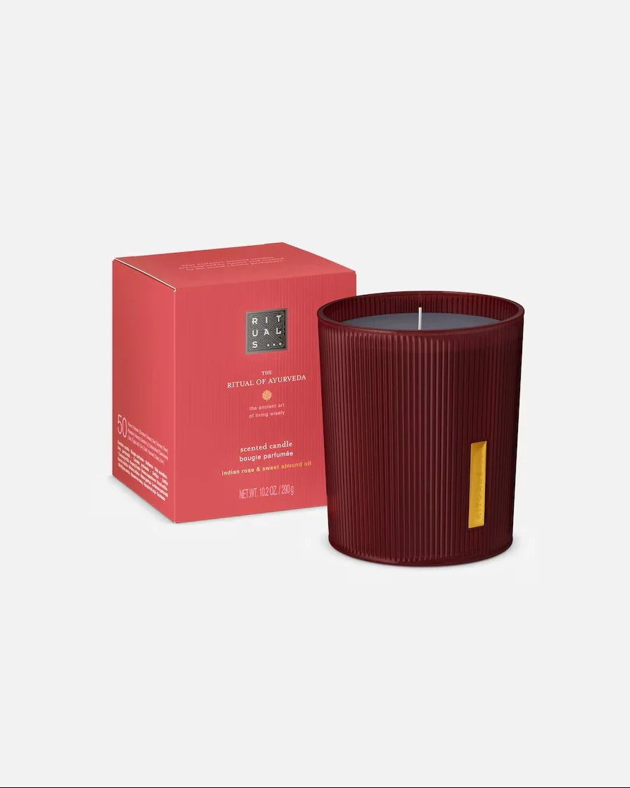 Dunkelrote Duftkerze „The Ritual of Ayurveda“ von Rituals im geriffelten Glas. Daneben steht die passende rote Verpackungsschachtel.