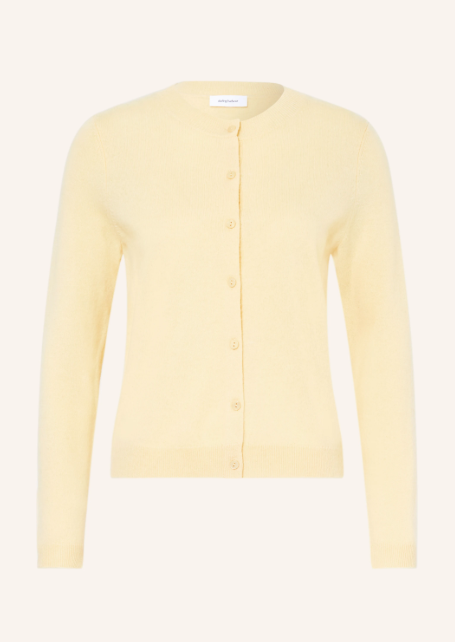 Buttergelber Cardigan aus Feinstrick mit Rundhalsausschnitt und Knopfleiste. Schmale Strickjacke mit farblich passenden Knöpfen vor hellem Hintergrund. Rippbündchen an langen Ärmeln und Saum.