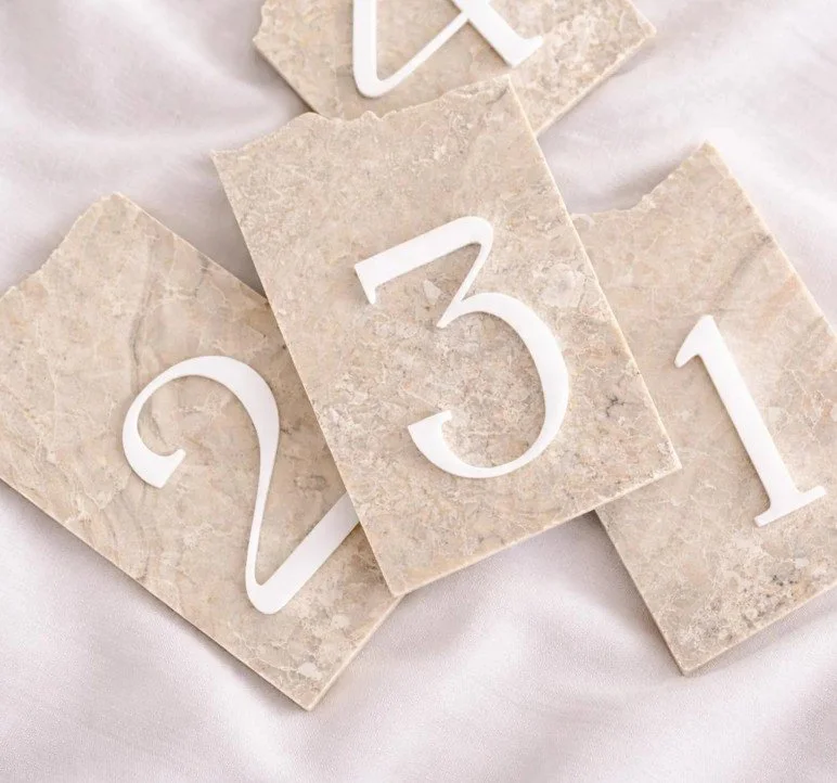 Eine Draufsicht auf vier flache, unregelmäßig geformte Steinplatten mit weißen Ziffern von 1 bis 4 auf einem hellen Seidenstoff.