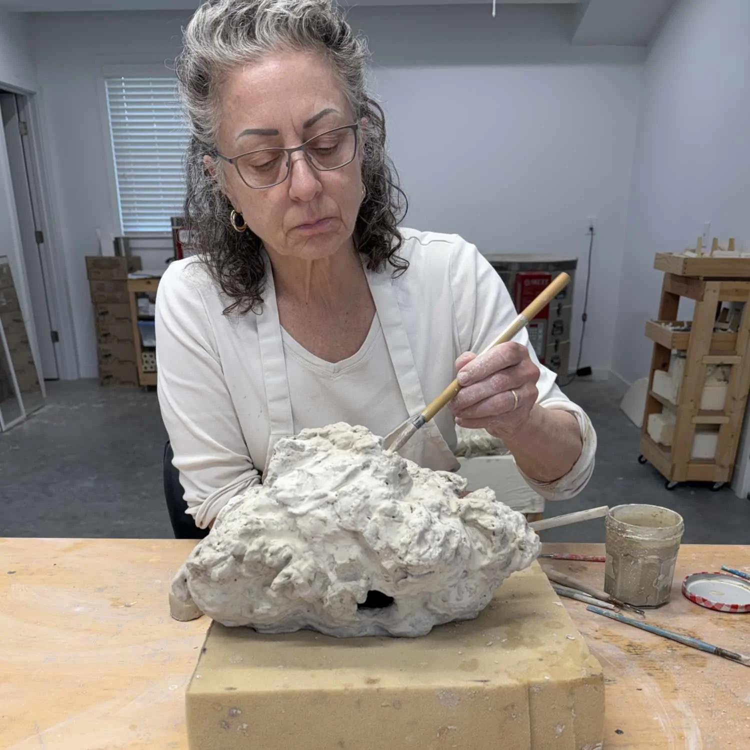 Lisa Hilton applying surface detail to a hand-built ceramic cloud sculpture in her studio, exploring texture and form