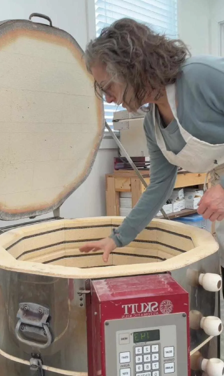 Ceramic kiln being opened in the studio revealing fired sculptures, showing the transformation of clay through heat