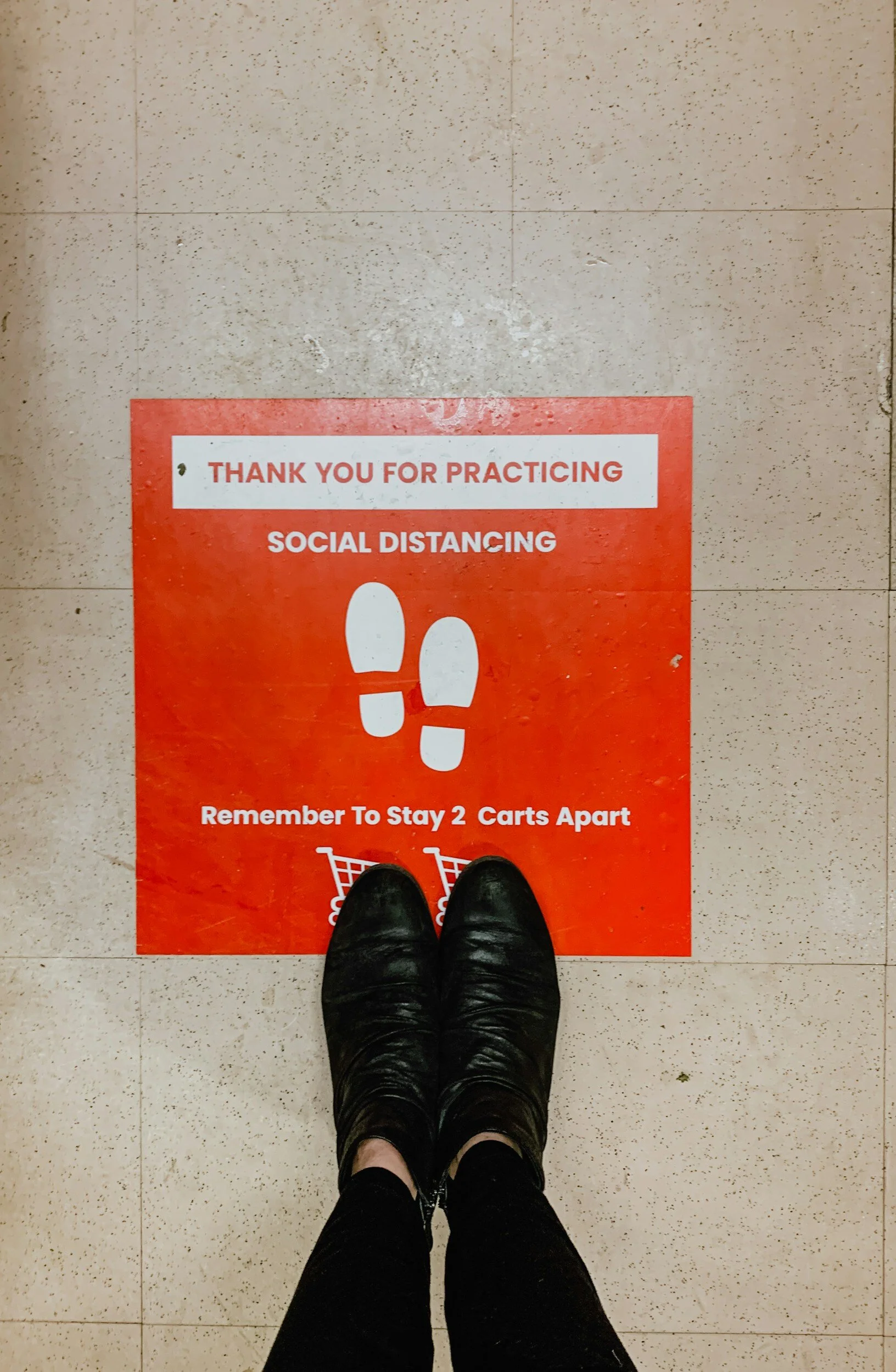 Person standing on social distancing floor sign in store