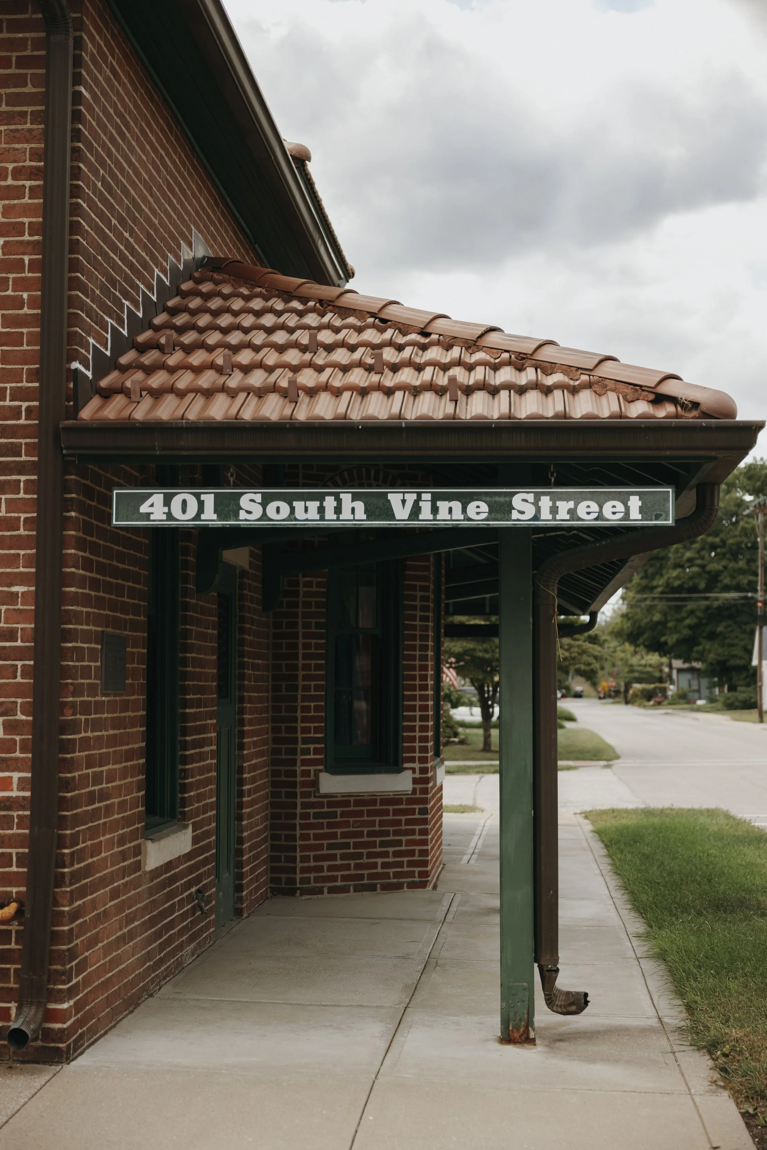 Street view of a brick building with a green overhang, displaying a sign that reads '401 South Vine Street.'